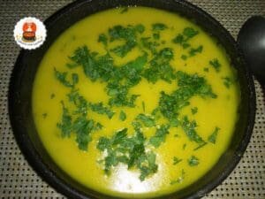Tigela preta com sopa espessa de inhame, com macarrão e salsa por cima.