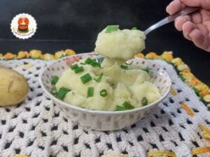 Tigela com purê de batata branco cremoso, decorado com salsinha.